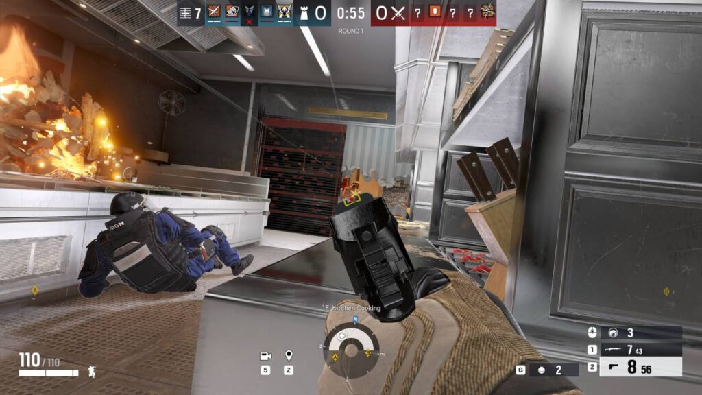 In-Game-Szene aus Rainbow Six Siege, in der ein Spieler mit gezogener Pistole durch eine zerstörte Küche vorrückt, während im Hintergrund eine Explosion lodert.