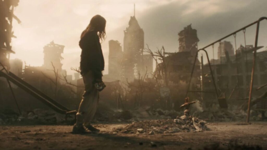 Eine einsame Person steht in den Ruinen von Raccoon City, während zerstörte Hochhäuser und verlassene Spielgeräte die trostlose Atmosphäre nach dem Ausbruch unterstreichen.