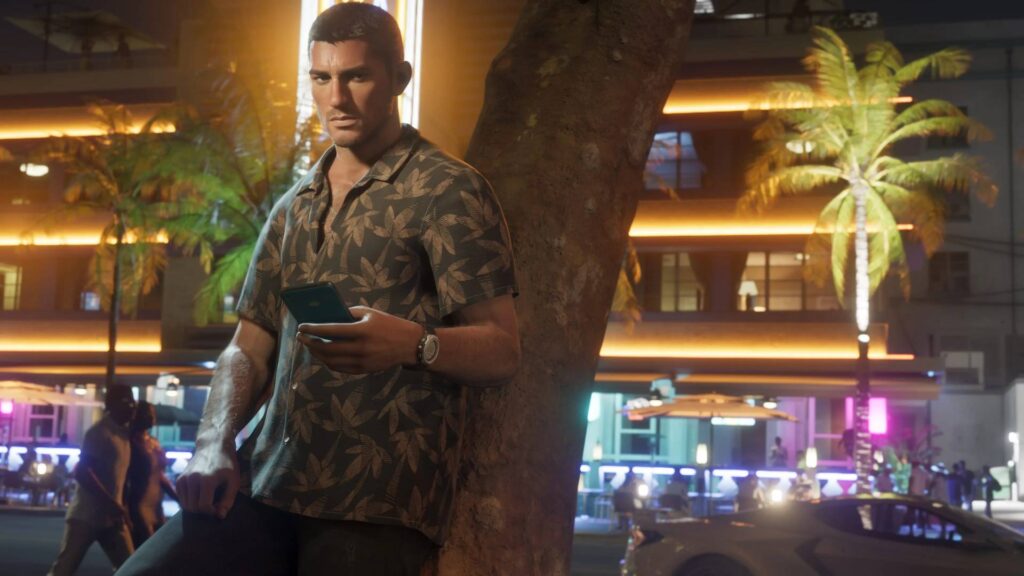Jason Duval steht in GTA 6 nachts vor einem beleuchteten Hotel und schaut auf sein Smartphone