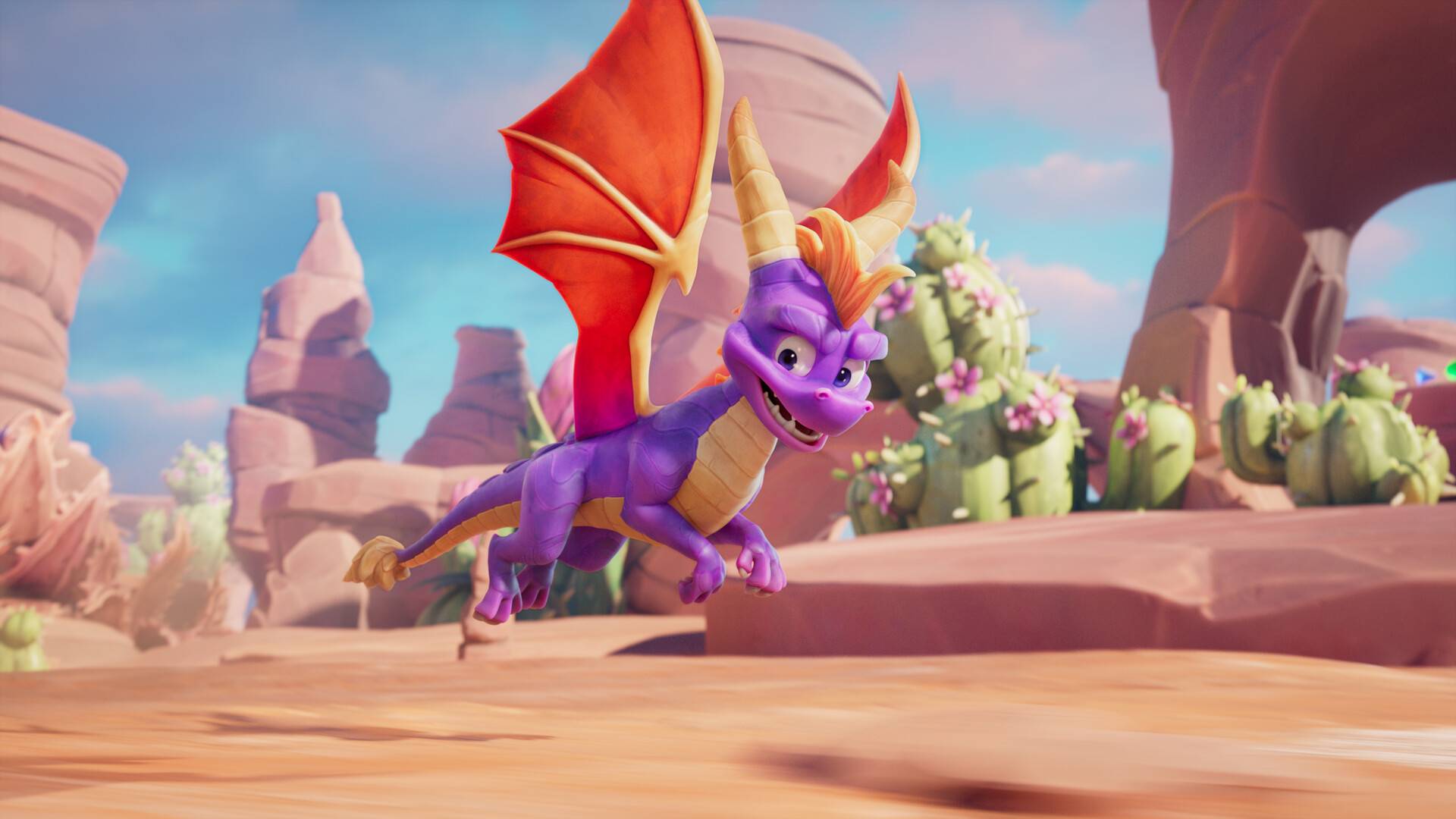 Spyro: A Realm Beyond zeigt den lila Drachen Spyro im Flug durch eine helle Wüstenlandschaft mit roten Felsen und Kakteen.