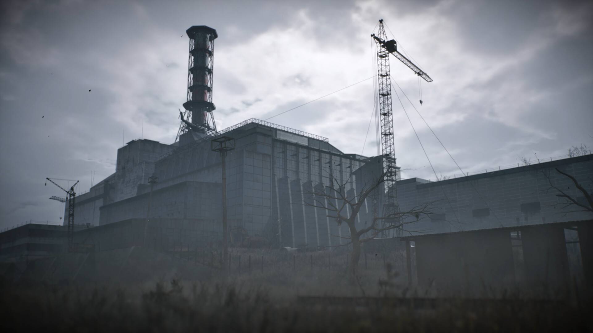 Vernebeltes Kernkraftwerk von Tschornobyl mit Reaktorgebäude, Kränen und düsterem Himmel in Stalker 2: Cost of Hope.
