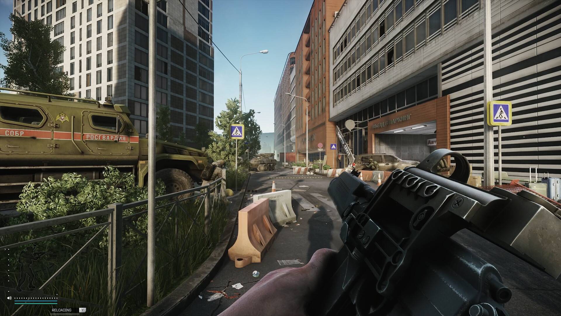 Escape from Tarkov zeigt eine Ego-Perspektive mit Waffe in einer abgesperrten Stadtstraße zwischen Militärfahrzeugen, Betonbarrieren und modernen Gebäuden.