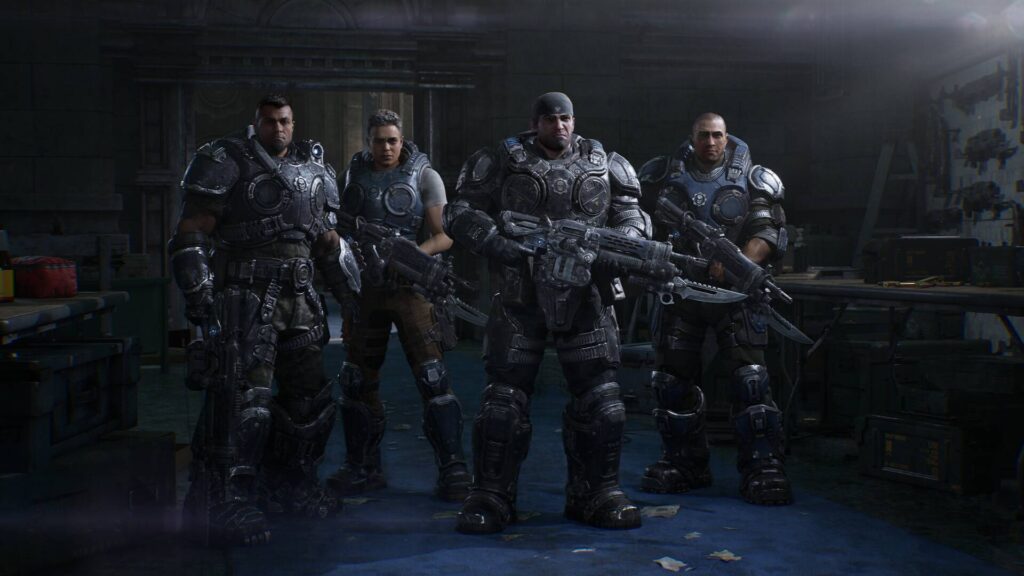 Vier schwer bewaffnete Soldaten in massiven Rüstungen stehen in einem düsteren Raum in Gears of War E-Day.