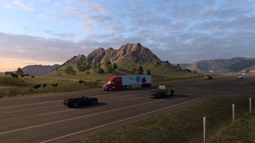 Ein roter Sattelschlepper fährt im American Truck Simulator an einer Bisonherde und einer felsigen Berglandschaft vorbei.