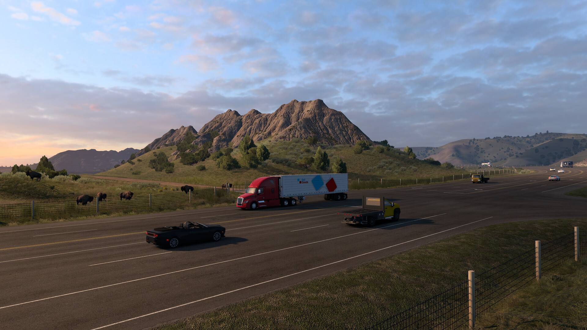 Ein roter Sattelschlepper fährt im American Truck Simulator an einer Bisonherde und einer felsigen Berglandschaft vorbei.