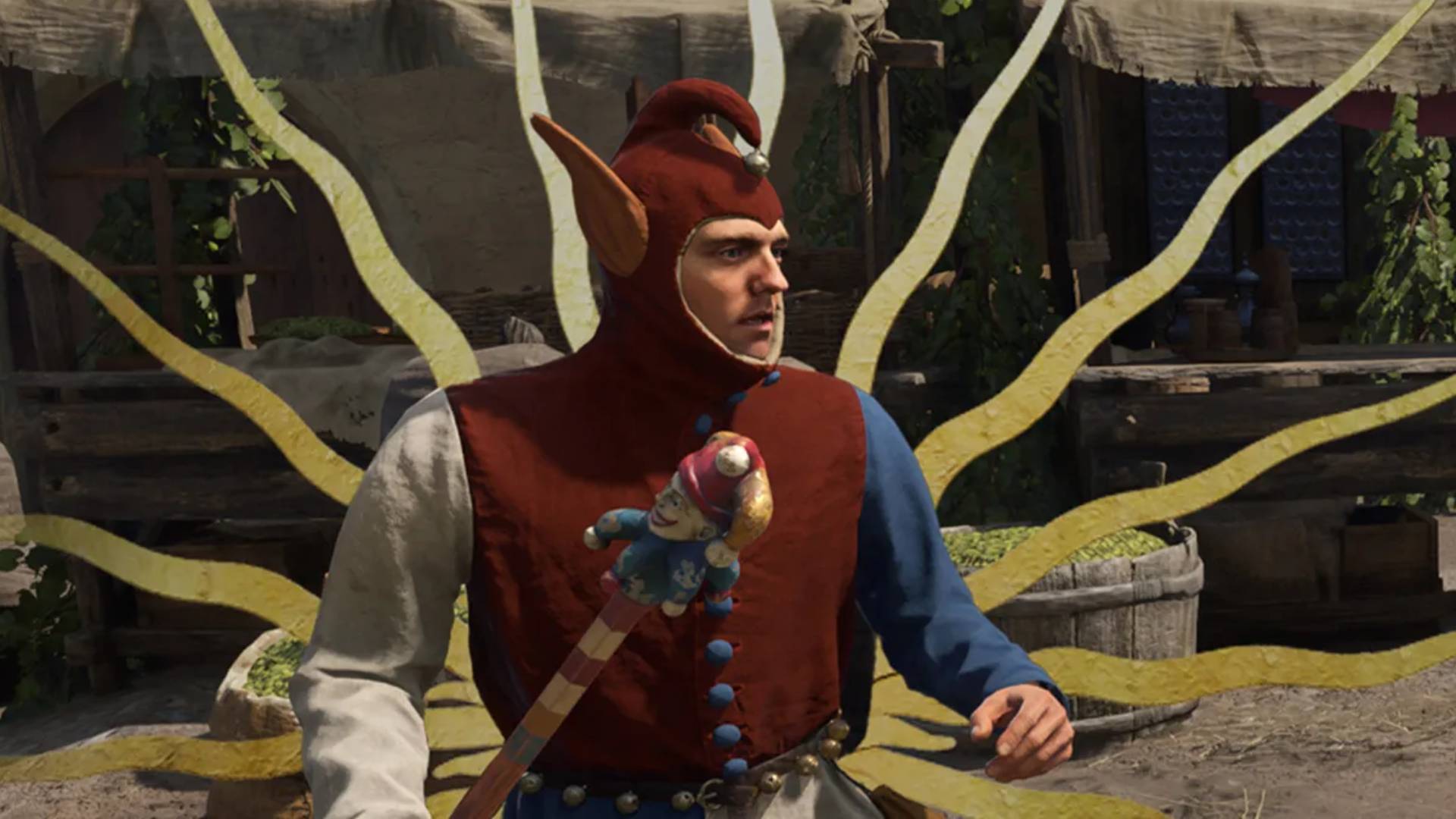 Ein Mann im Narrenkostüm steht in Kingdom Come Deliverance 2 vor einem Marktstand mit gelben Bändern im Hintergrund.